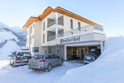 a building with two cars parked in the snow at Eberharthof in Saalbach-Hinterglemm
