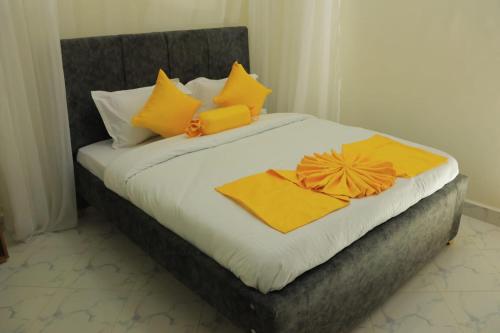 ein Bett mit gelben und orangefarbenen Kissen darauf in der Unterkunft Downtown Retreat Homes in Kisii