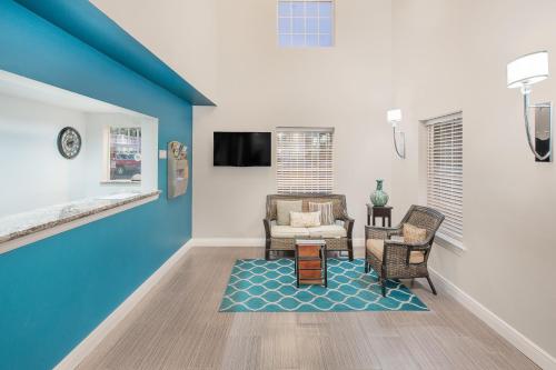 a living room with a blue accent wall and chairs at Super 8 by Wyndham Bay St. Louis in Bay Saint Louis