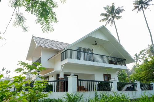 a white house with a balcony and palm trees at Paradise Riviera in Ernakulam