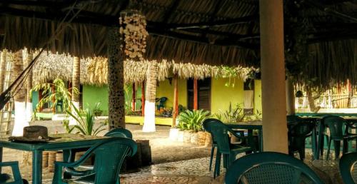 a restaurant with green tables and chairs in front of a building at Eco-Hotel Playa Quilombo in Las Lisas