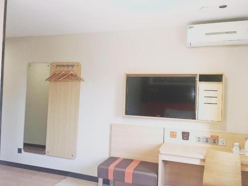 a room with a kitchen with a microwave and a table at 7 Days Premium JiNan Jingshi Road Qilu Children's Hospital Exhibition Center in Jinan