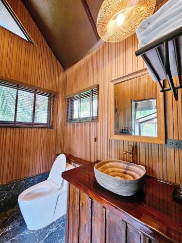 a bathroom with a wooden wall with a wooden tub at Cheewatra Farmstay Coconut House in Ban Tha Maphrao