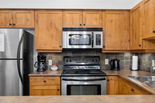 a kitchen with a stove and a microwave at Settlers Crossing #29 By Bear Country in Sun Peaks