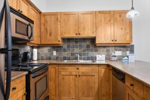 a kitchen with wooden cabinets and a stove top oven at Settlers Crossing #29 By Bear Country in Sun Peaks