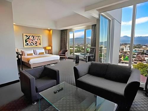 Sintesa Peninsula Hotel في مانادو: غرفة فندق بها سرير وأريكة