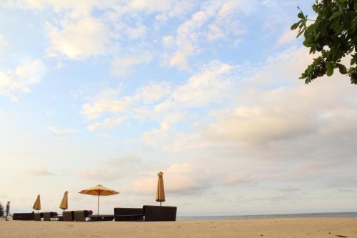 a group of umbrellas and chairs on a beach at Anema Wellness Villa & Spa Gili Lombok - Diving Center PADI in Tanjung