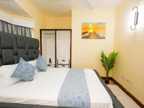 a bedroom with a large white bed with blue pillows at Cosy 1 BR with Swimming Pool & Garden & 25 Mins to Airport - C04 in Mombasa