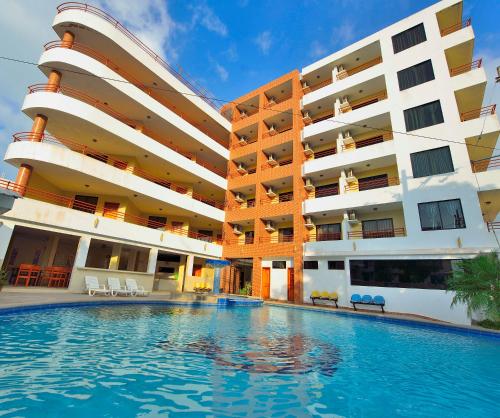 um hotel com piscina em frente a um edifício em Hotel La Aldea em Atacames