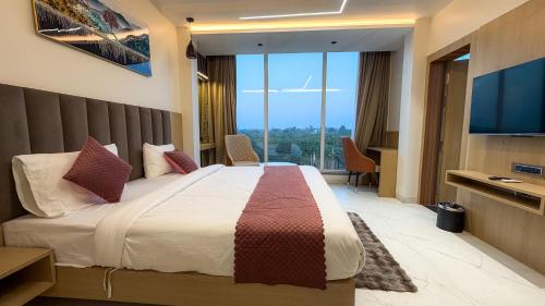 een hotelkamer met een bed en een flatscreen-tv bij Travinities Hotel Shree Ji Palace in Ujjain