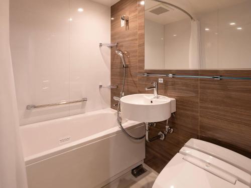 a bathroom with a sink and a tub and a toilet at Comfort Hotel Mito in Mito
