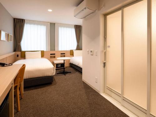una camera d'albergo con due letti e una scrivania di Comfort Hotel Mito a Mito