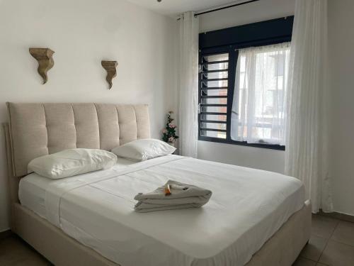 a bedroom with a white bed with towels on it at T3 Rosa - 59m2 avec piscine commune - Saint-Leu in Saint-Leu