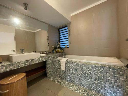 a bathroom with a tub and a sink and a mirror at T3 Rosa - 59m2 avec piscine commune - Saint-Leu in Saint-Leu