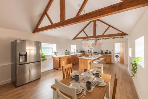 a kitchen and dining room with a table and a refrigerator at Stunning 5-bed Barn Conversion in Newark-on-Trent by Renzo, Beautiful Surroundings, Sleeps 10! in Besthorpe