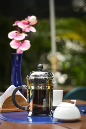 a tea pot on a table with a vase of flowers at Casa Hotel Jardin Azul in Cali