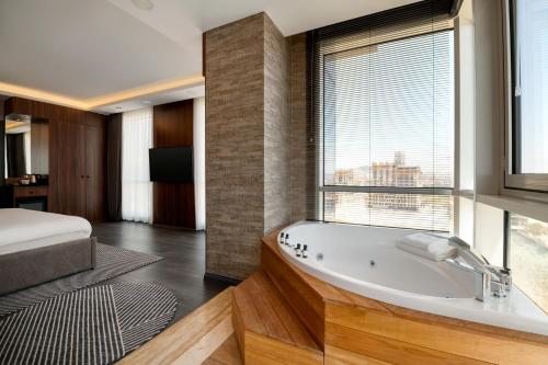 a bathroom with a tub and a bed and a window at La Quinta By Wyndham Istanbul Kartal in Istanbul