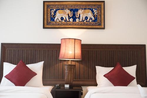 True Siam Rangnam Hotel في بانكوك: غرفة فندقية بسريرين وصورة على الحائط
