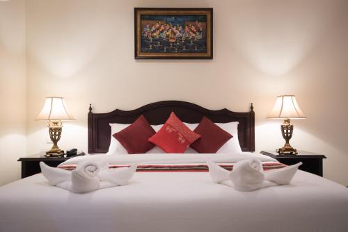a bedroom with a white bed with red pillows at True Siam Rangnam Hotel in Bangkok