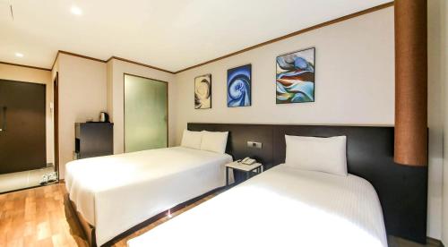 two beds in a hotel room with two beds at Sun Land Hotel Jeju in Jeju