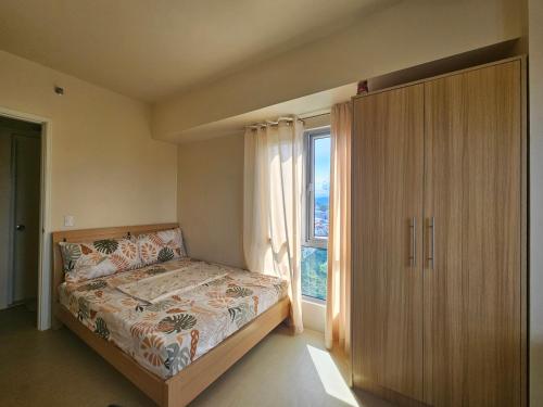 a bedroom with a bed and a large window at Avida Abreeza 1bedroom with balcony in Davao City
