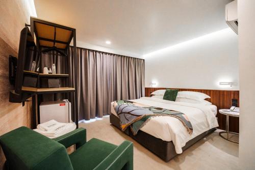 a bedroom with a bed and a couch and a chair at Palma Hotel in Bangkok