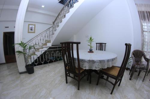 a dining room with a table and chairs and a staircase at Grindlays Villa in Weligama