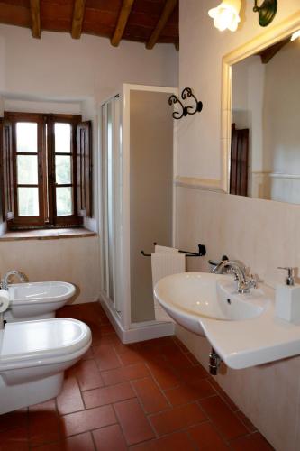 a bathroom with two sinks and a toilet and a mirror at Il Poggetto in Greve in Chianti