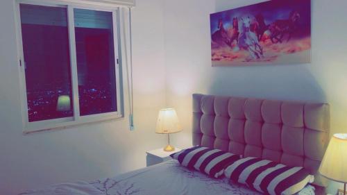 1 dormitorio con 1 cama con cabecero rosa y ventana en شقق ڤيڤا - viva Apartments, en Amán