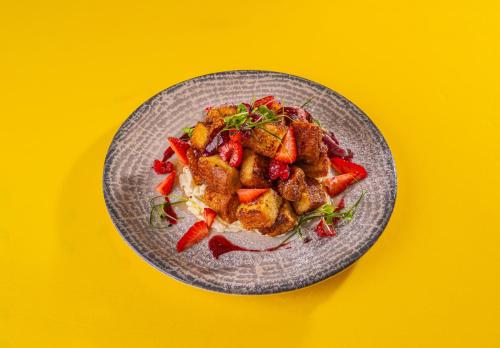 a plate of food with strawberries on a yellow background at AG Hotel in Abu Dhabi
