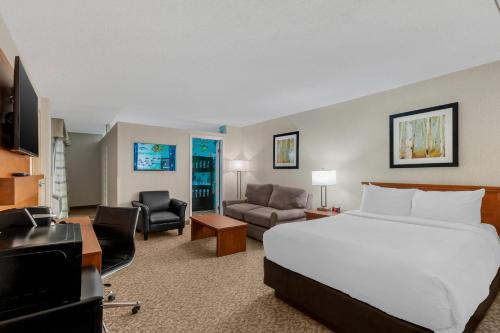 Clarion Hotel & Suites في براندون: غرفة فندقية مع سرير وغرفة معيشة