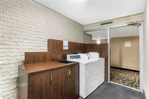 Clarion Hotel & Suites في براندون: غسالة ومجفف في غرفة مع جدار من الطوب