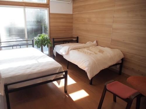 two beds in a room with wooden walls and a window at Lake&Mountain Hamamatsu inn in Hamamatsu