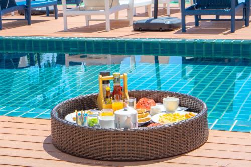 パナワビーチにあるPhuket Boat Quay Hotel Panwa Beachのプールの横に食べ物と飲み物が詰まったバスケット