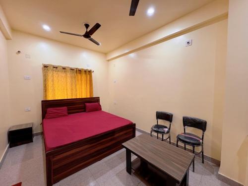 ein Schlafzimmer mit einem Bett und zwei Stühlen und einem Tisch in der Unterkunft Studio 305 Signature Heaven in Deoghar