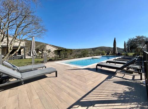 a swimming pool with chaises and umbrellas next to at Mas de Veyras - Gîtes 5 étoiles en Ardèche in Lachapelle Sous Aubenas