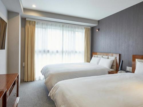Una habitación de hotel con dos camas y una ventana. en EZ HOTEL Kansai Airport Seaside, en Izumisano