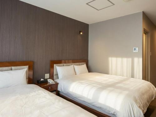 two beds sitting next to each other in a bedroom at EZ HOTEL Kansai Airport Seaside in Izumi-Sano