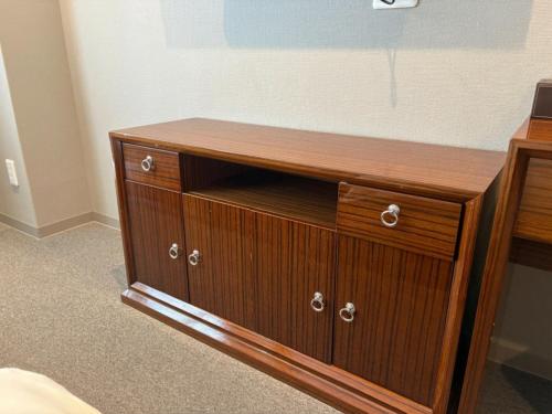a wooden dresser in a room with a bed at EZ HOTEL Kansai Airport Seaside in Izumi-Sano