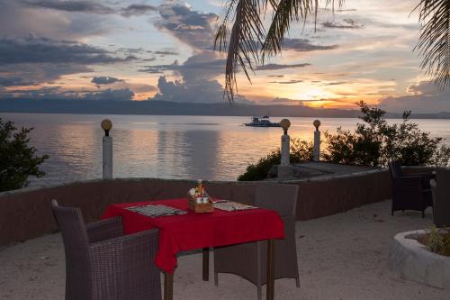 a table with a red table cloth and a boat in the water at Polaris Beach and Dive Resort Inc in Loon