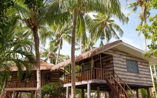 een huis met palmbomen ervoor bij Polaris Beach and Dive Resort Inc in Loon