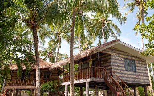 a house with palm trees in front of it at Polaris Beach and Dive Resort Inc in Loon