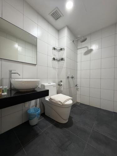 een badkamer met een wastafel, een toilet en een spiegel bij Chambers Klcc Suites Esten in Kuala Lumpur