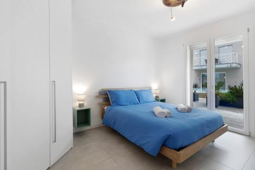a white bedroom with a blue bed and a balcony at Albiceleste Prime Location in Peschiera del Garda