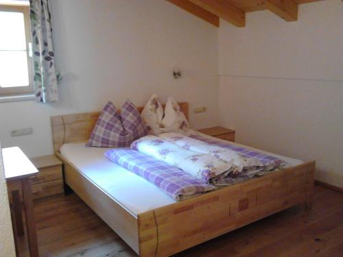 a bedroom with a wooden bed with pillows on it at Pfaffenreitherhof in Uttendorf