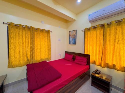 ein rotes Bett in einem Zimmer mit gelben Vorhängen in der Unterkunft Studio 306 Royal Urban in Deoghar