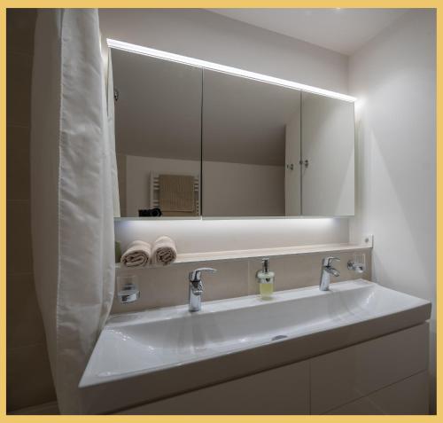 ein Badezimmer mit einem weißen Waschbecken und einem Spiegel in der Unterkunft Le Cocon Alpin I Megève in Megève