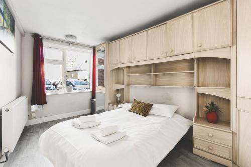 Schlafzimmer mit einem großen weißen Bett und Holzschränken in der Unterkunft Spacious 4BDR House with Parking by Heathrow in Hillingdon