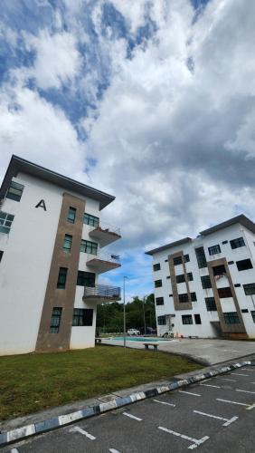 CC Regalia Homestay Kota Samarahan Kuching Sarawak في Kota Samarahan: مبنيين شاهقين في موقف سيارات مع سماء