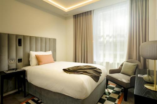 a bedroom with a bed and a chair and a window at The Wellington Glasgow by Adina in Glasgow